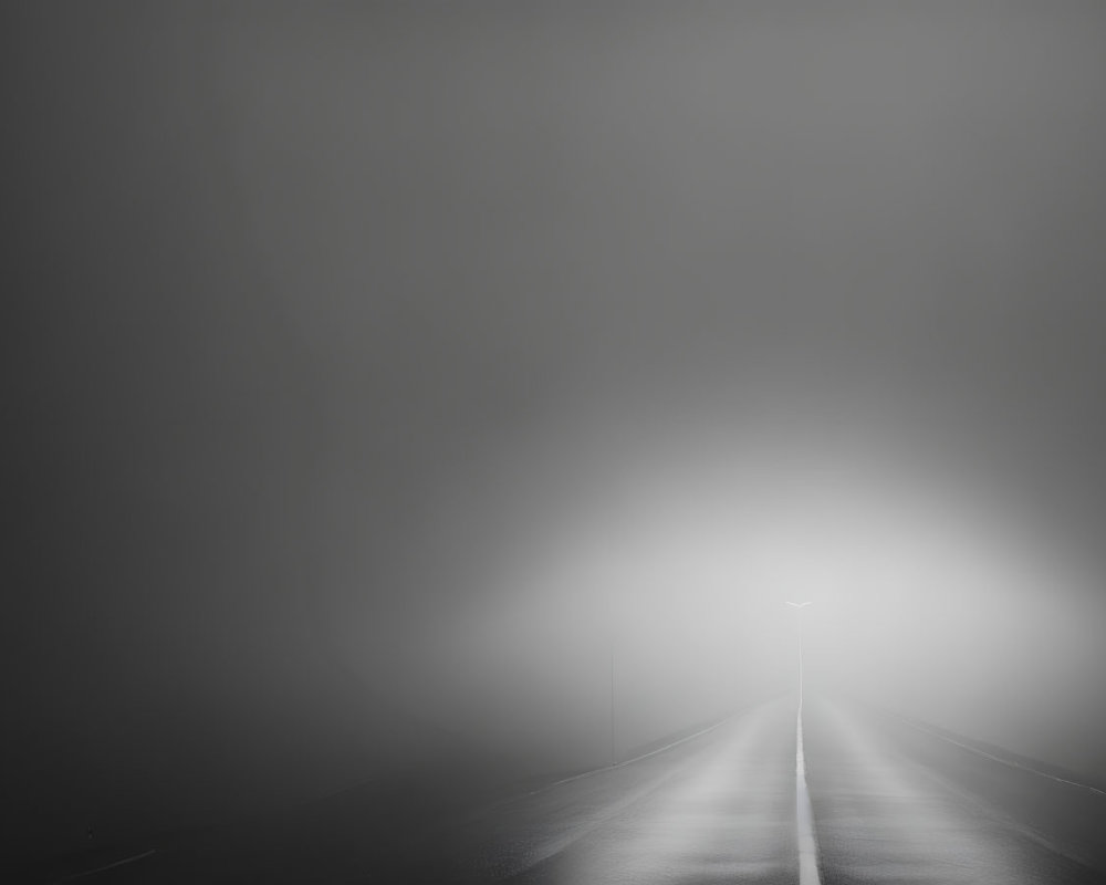 Desolate road under dimly lit streetlight in mist