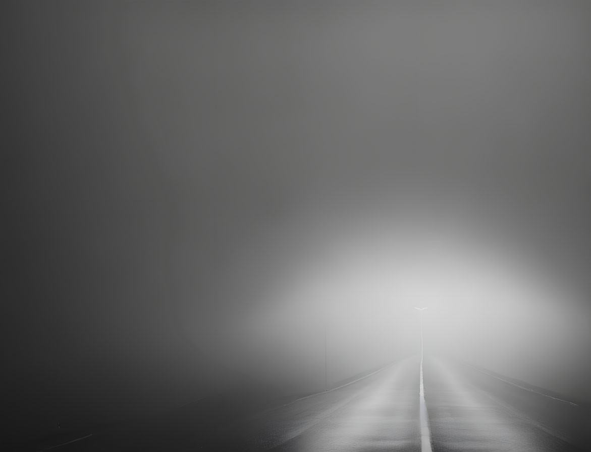 Desolate road under dimly lit streetlight in mist