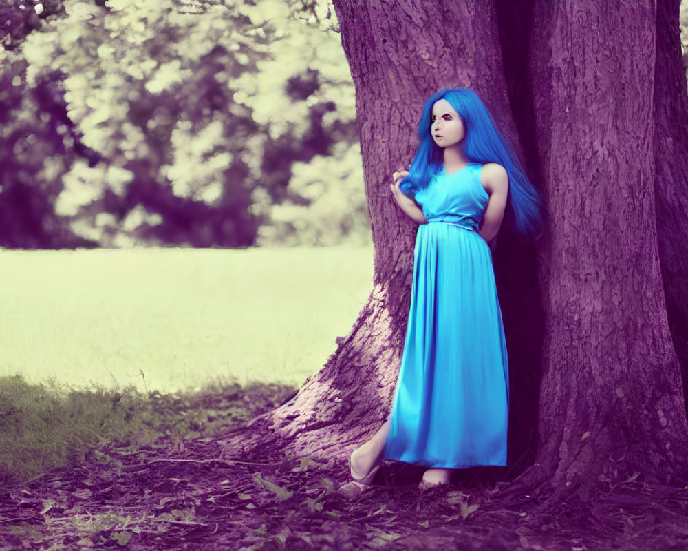 Blue-haired woman in matching dress gazes into the distance by tree in woodland