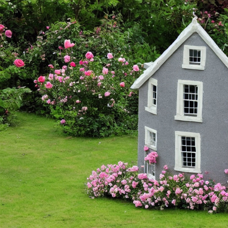 Miniature gray house with white trimmings in lush garden setting