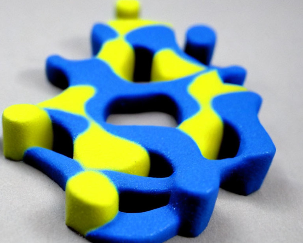 Blue and Yellow 3D-Printed Puzzle Piece on Grey Background