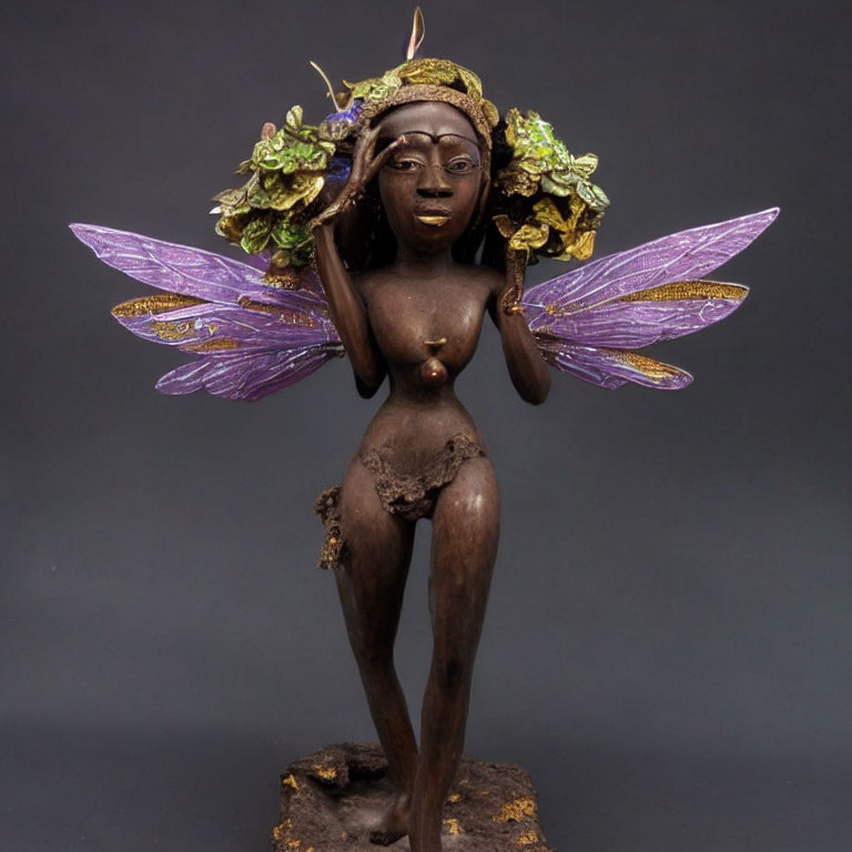 Fantasy female faerie figurine with purple wings and green headdress on dark background
