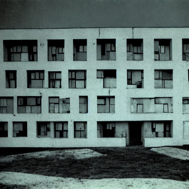 Grayscale image: Old, rundown apartment building with open and closed windows.
