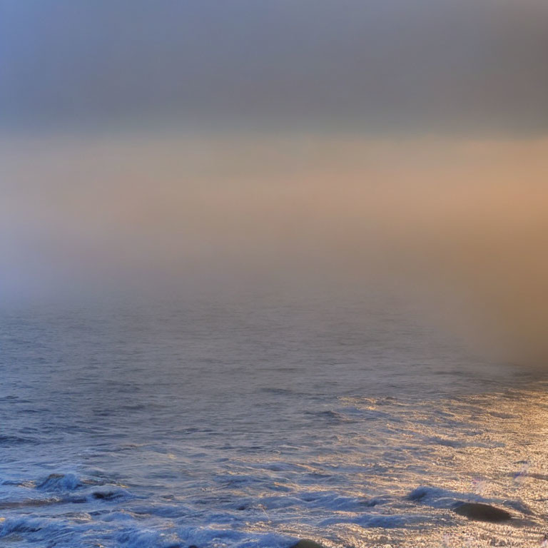 Misty sunset seascape with warm diffused light over waves