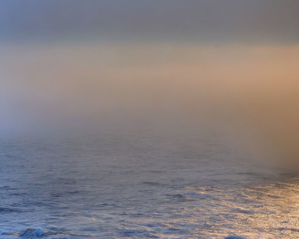 Misty sunset seascape with warm diffused light over waves