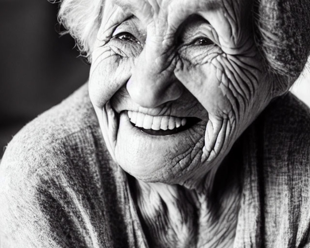 Elderly woman in headscarf smiling in black and white portrait