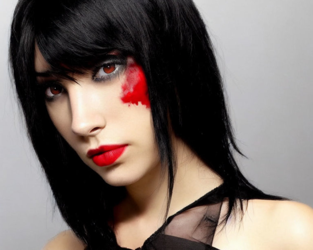Intense gaze with red eye makeup and black hair on grey background