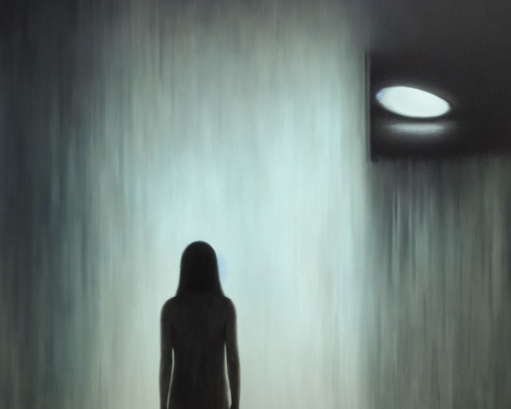 Silhouette of person in heavy rain under streetlight