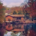 Autumnal riverside scene with cozy cottage, bridge, and colorful foliage