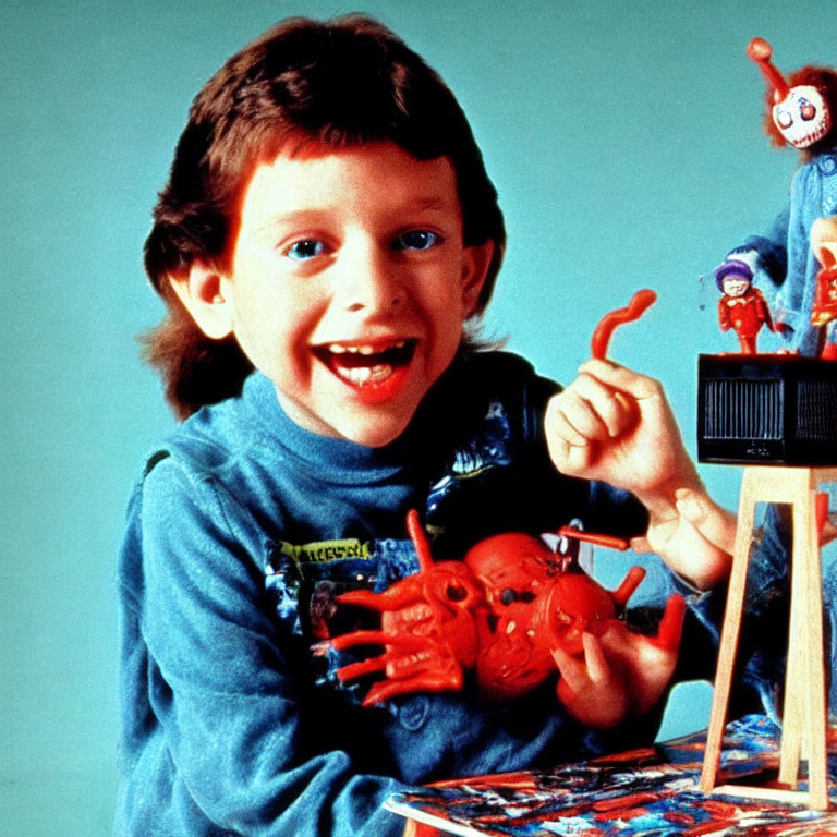 Smiling boy with toy and clown puppet on blue backdrop