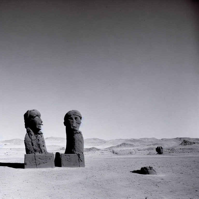 Ancient stone statues of pharaoh-like figures in desert landscape