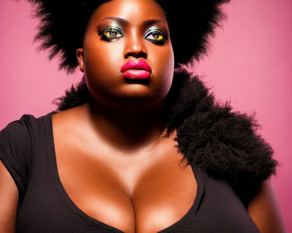 Confident woman with striking makeup and afro on pink background