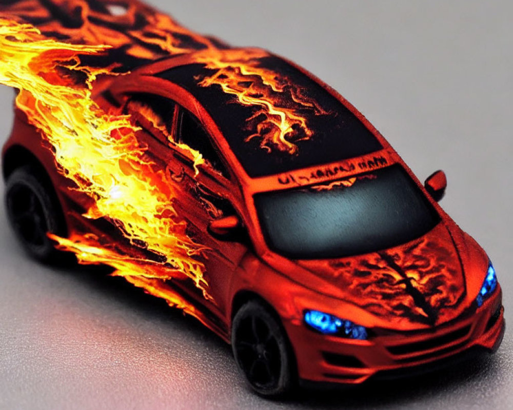 Red Toy Car with Flame Decals and Black Wheels on Grey Surface