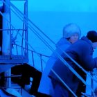 Three People in Winter Coats Watching Fleet of Ships on Misty Sea