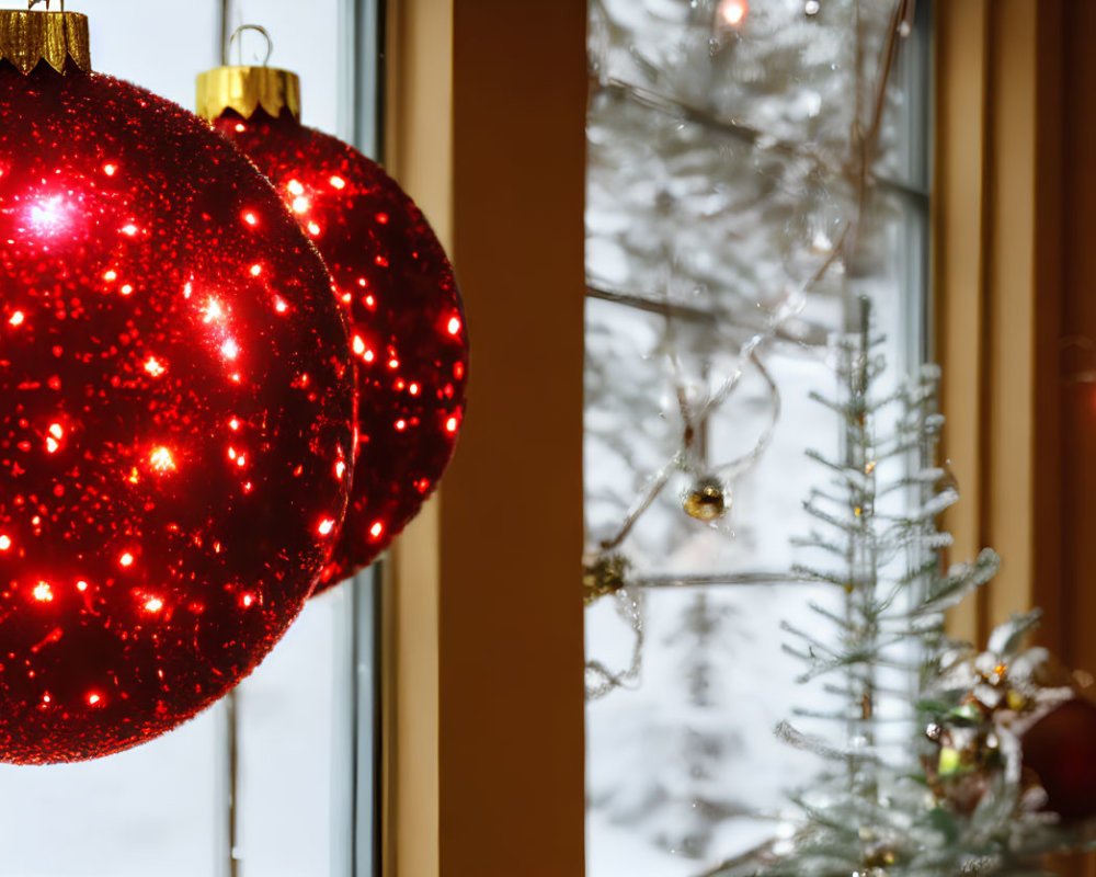 Vibrant red Christmas baubles by window with snowy landscape