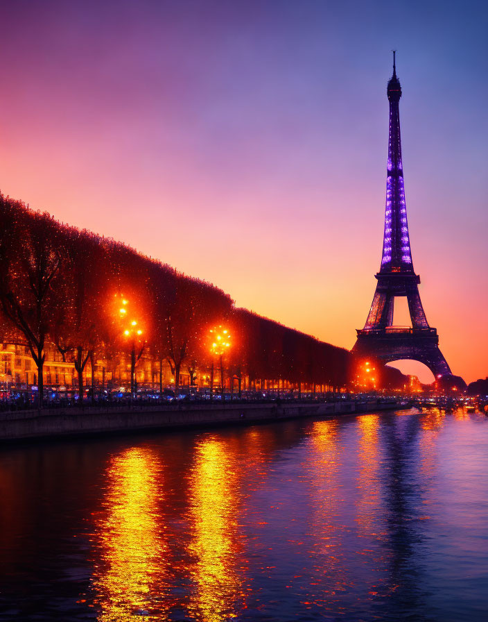 Iconic Eiffel Tower and riverside trees at twilight with vibrant sky over Seine River.