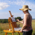 Bearded artist painting outdoors with blue sky and green fields
