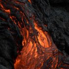 Winged figure in fiery volcanic landscape with lava and dark cliffs