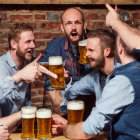 Group of men laughing and toasting with beer glasses at a bar