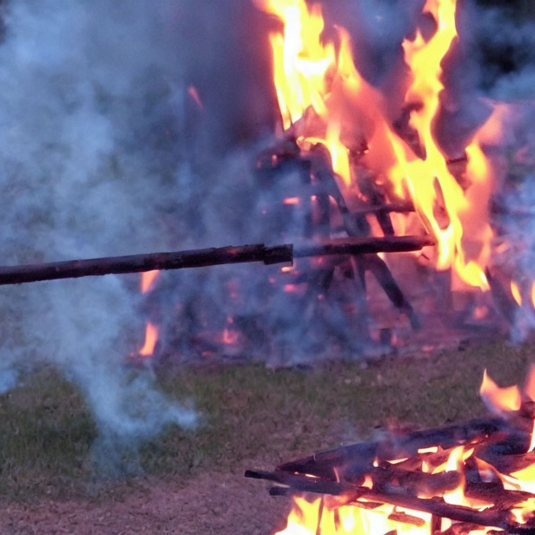 Burning wooden sticks close-up over outdoor bonfire