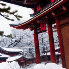 Snow-covered shrine with red lanterns in wintry landscape and Japanese architecture.