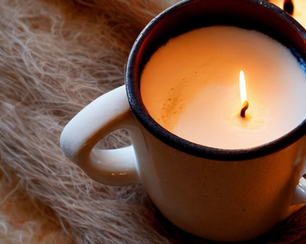 Ceramic mug with lit candle on fluffy surface