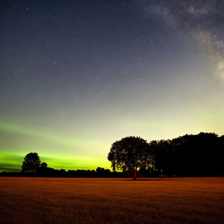 Serene field under starry night sky and Milky Way with sunset glow