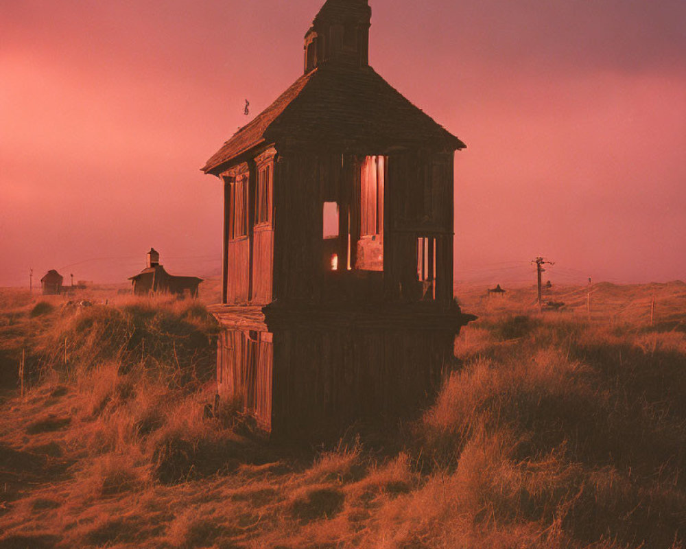 Dilapidated old wooden house in field at dusk with glowing light