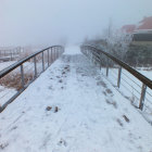 Snowy cobblestone bridge and gothic castle in foggy winter scene