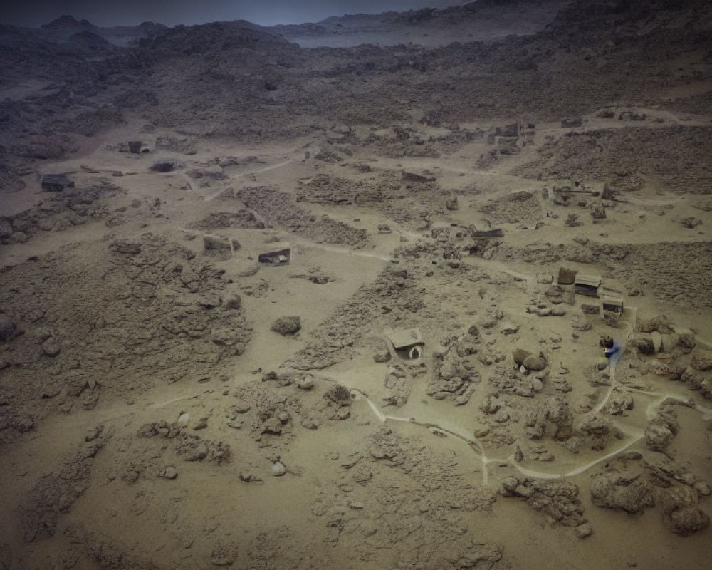 Aerial view of archaeological site with exposed ruins and person in rugged terrain