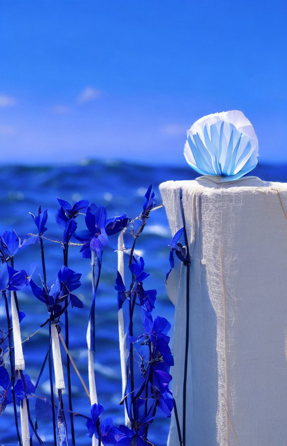 Tranquil beach scene with white cloth, blue decoration, and vibrant flowers