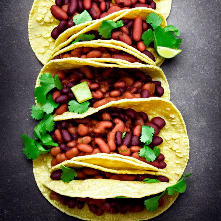 Mexican-style red bean-filled corn tortillas with cilantro and lime on dark background
