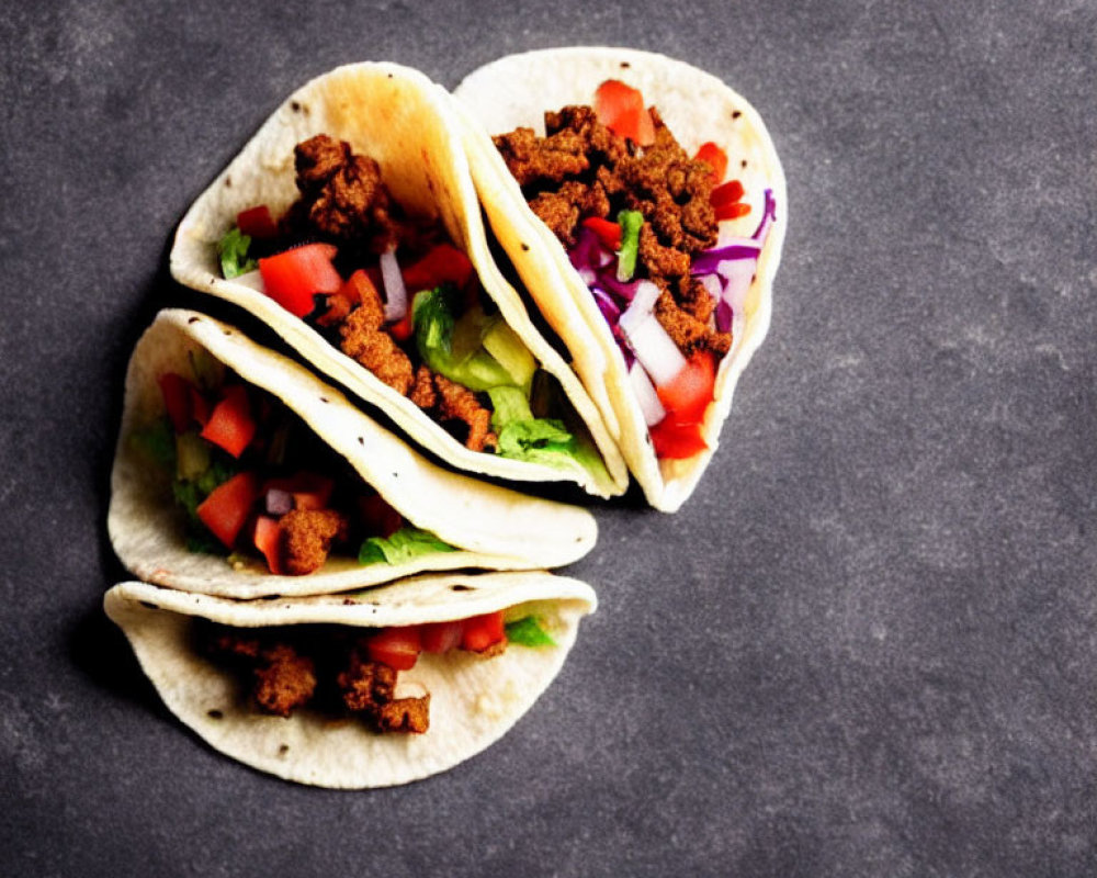 Three Ground Meat Tacos with Lettuce, Tomatoes, and Red Onions
