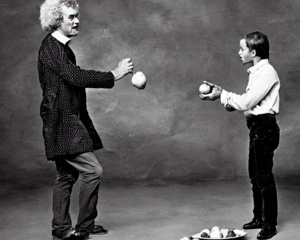 Adult and child juggling balls in front of each other