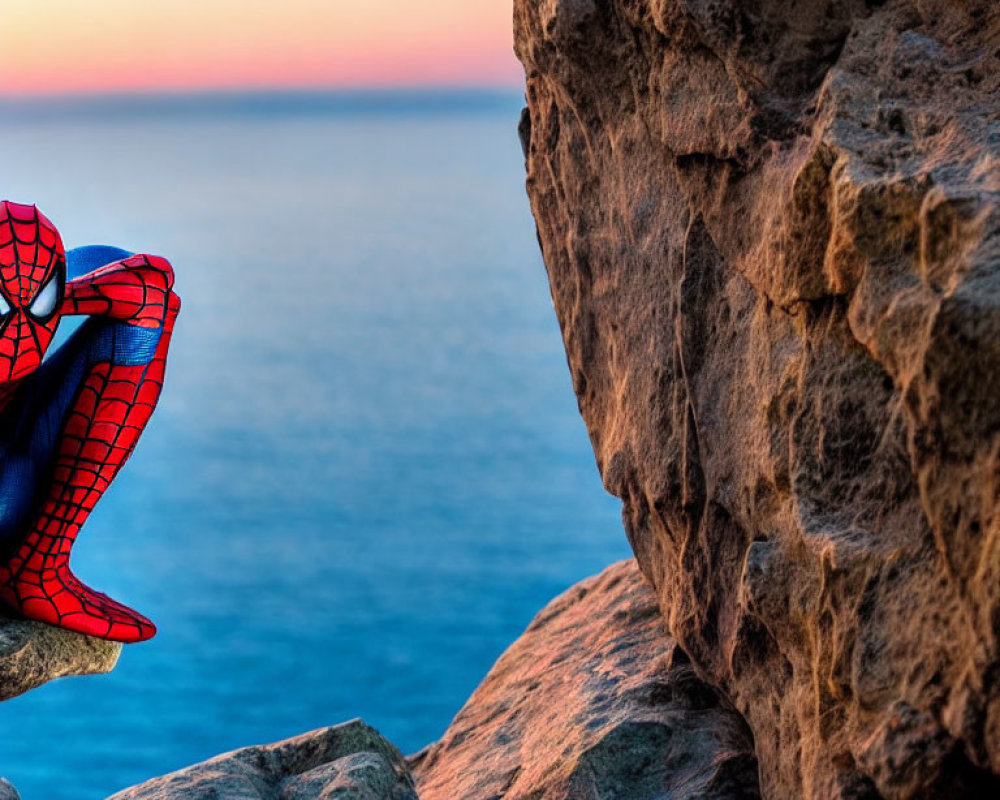 Person in Spider-Man Costume on Rocky Cliff with Ocean Sunset
