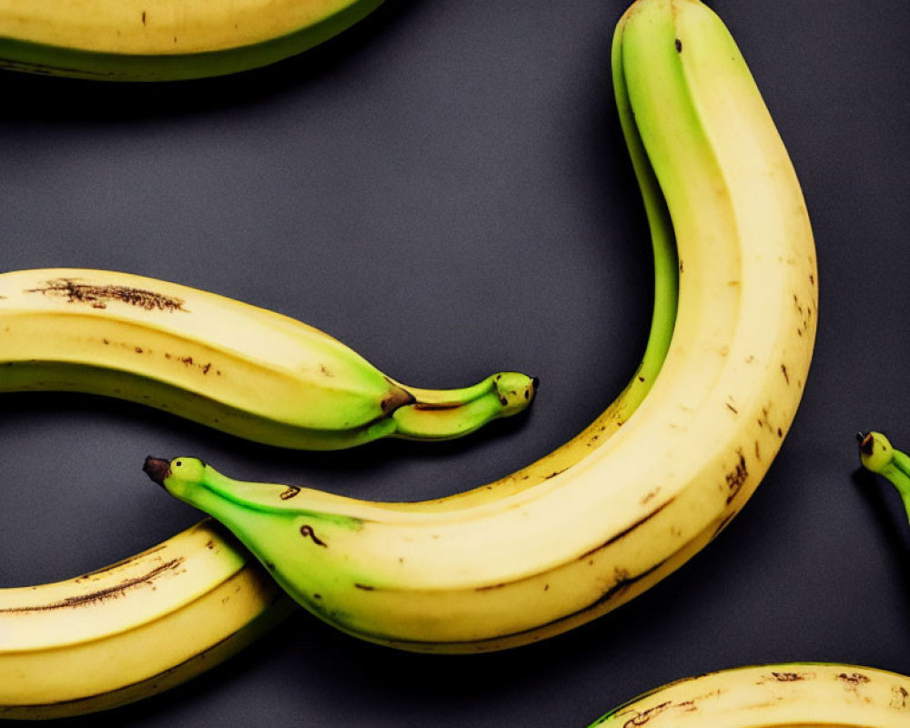 Bananas with painted eyes and mouths on dark background