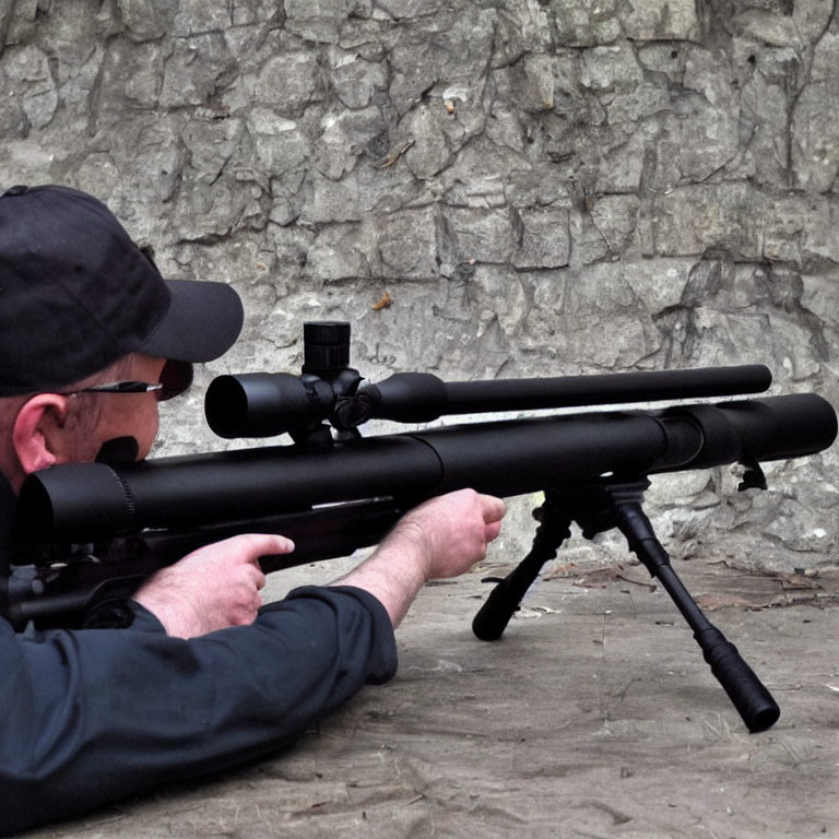 Person in Black Cap Aiming Sniper Rifle at Stone Wall