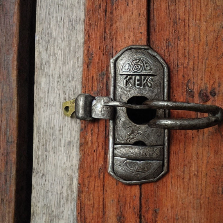 Detailed close-up: old metal sliding bolt lock with decorative patterns on wooden door