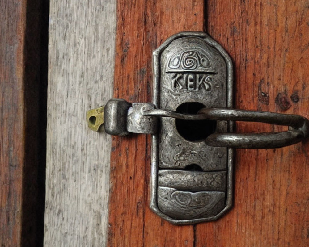 Detailed close-up: old metal sliding bolt lock with decorative patterns on wooden door