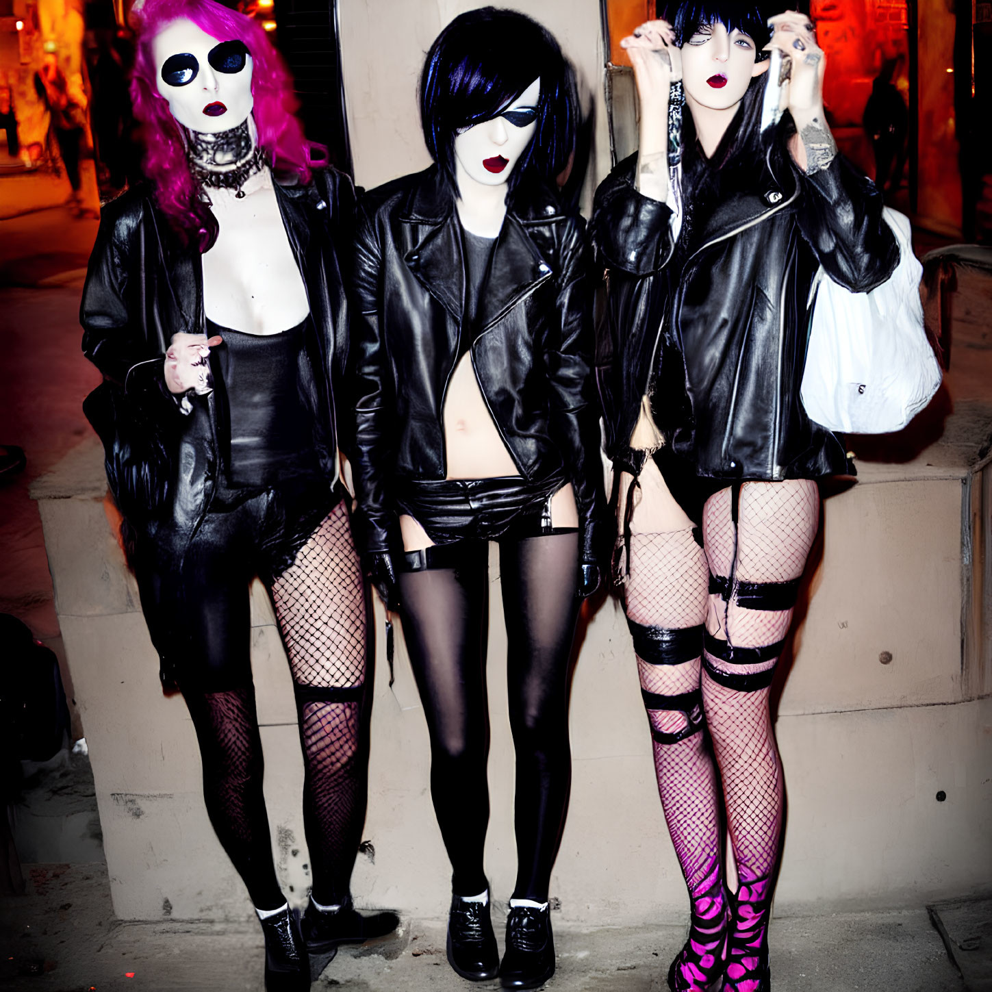 Three people in punk-inspired attire on city street at night