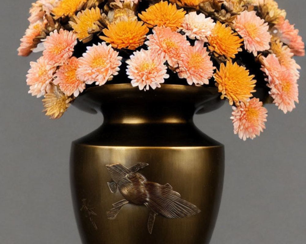 Bronze vase with embossed bird design and pink-orange chrysanthemums