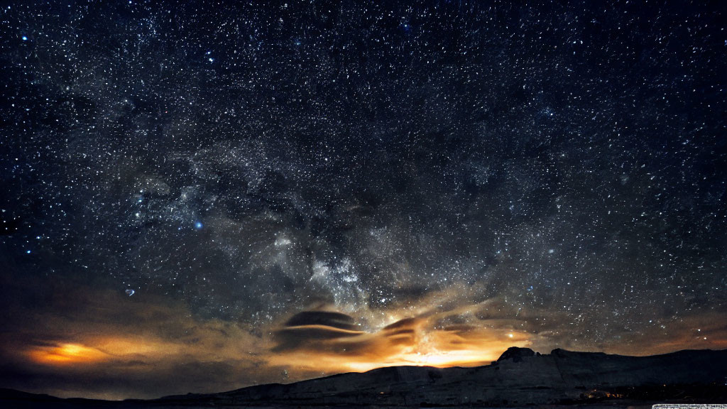Starry Night Sky Silhouette of Mountain Range with Warm Glow