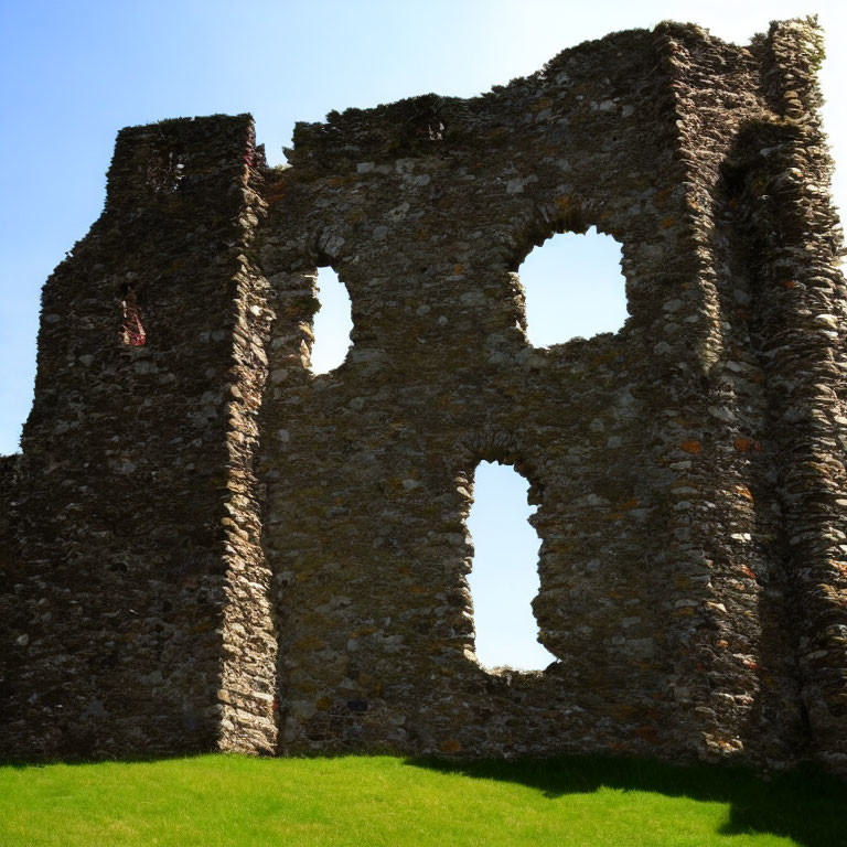 Ancient stone building ruins with large arched windows on clear blue sky