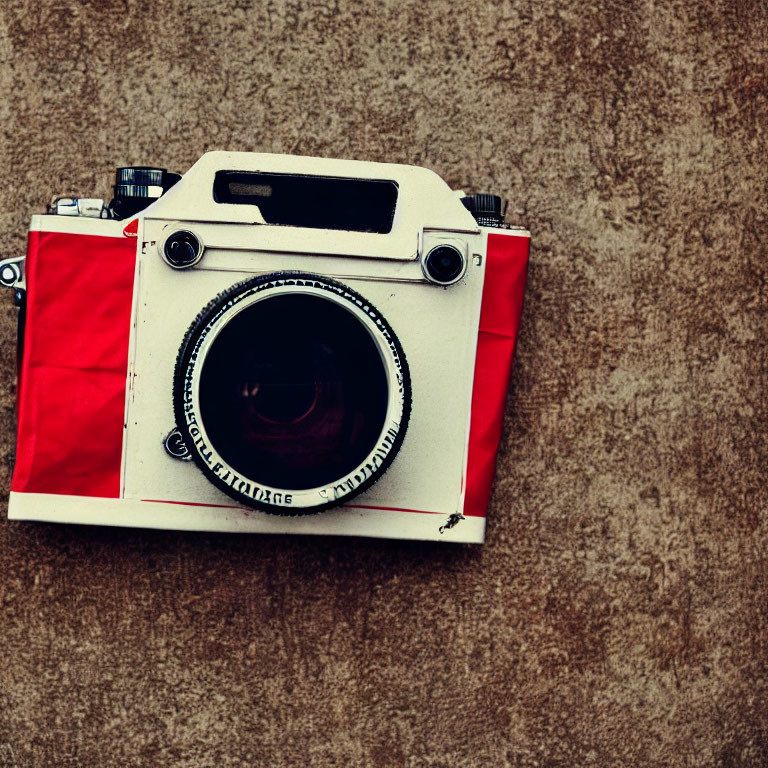 Vintage Red and White Camera with Large Lens on Textured Beige Wall