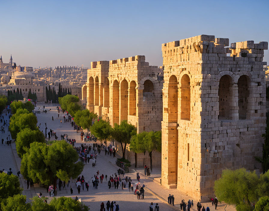 Stone city walls and arches frame a bustling square at golden hour, with a cityscape in the