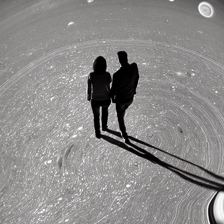 Two people casting long shadows on starry space surface