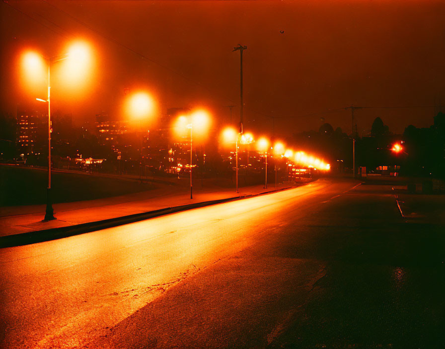 Nighttime cityscape with warm streetlights illuminating wet road