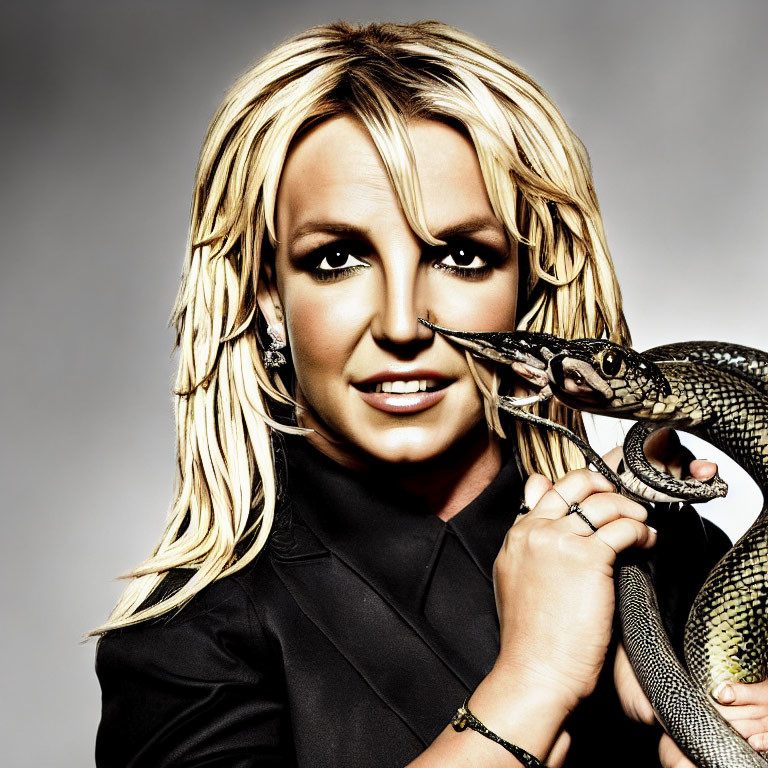 Blonde woman in black outfit with snake, looking at camera