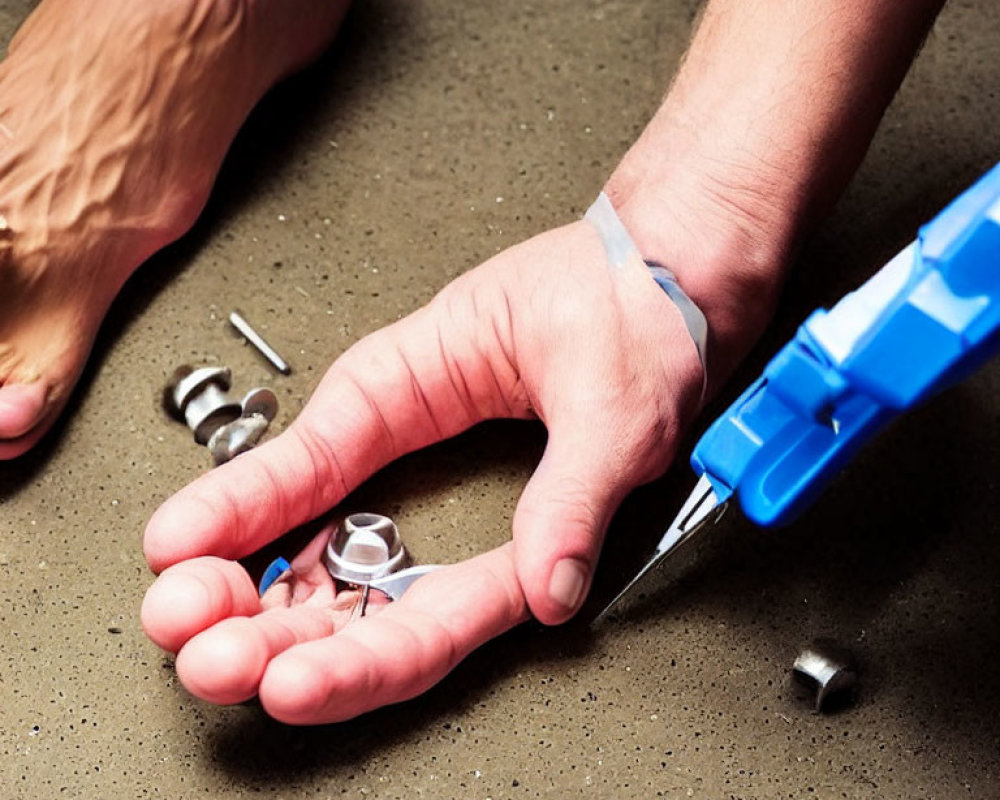 Person injecting hand with blue syringe among scattered mechanical parts