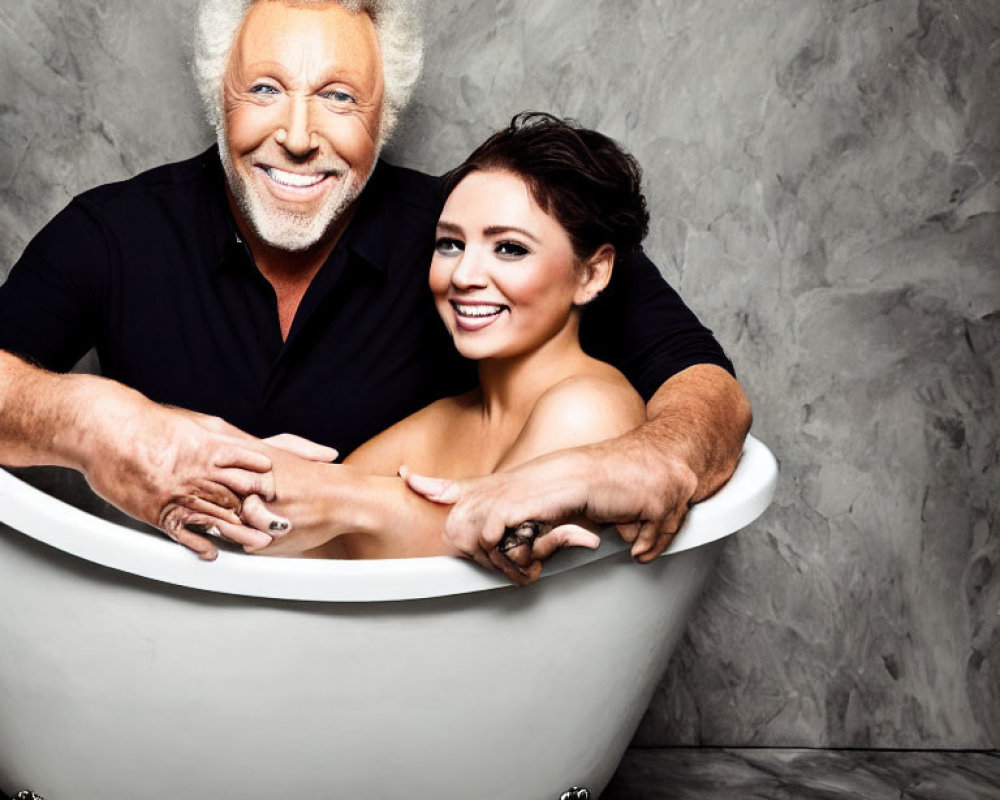 Silver-haired man and brown-haired woman smiling in bathtub